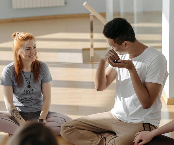 Group of diverse people sitting on yoga mats in a bright, welcoming studio.